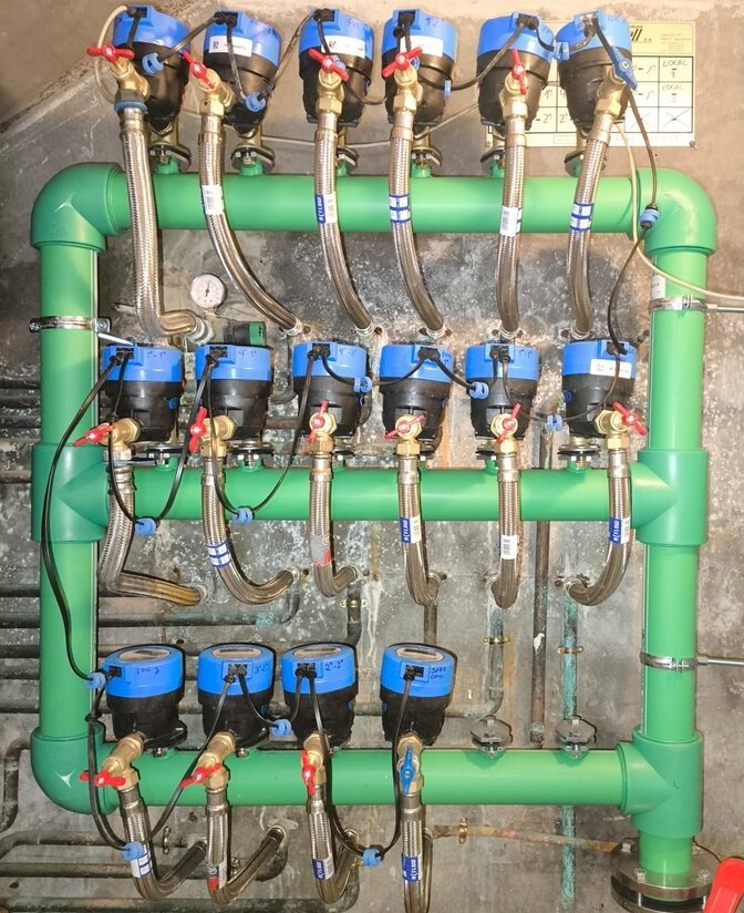 Conjunto de contadores de agua con tuberías verdes multicapa y conexiones metálicas